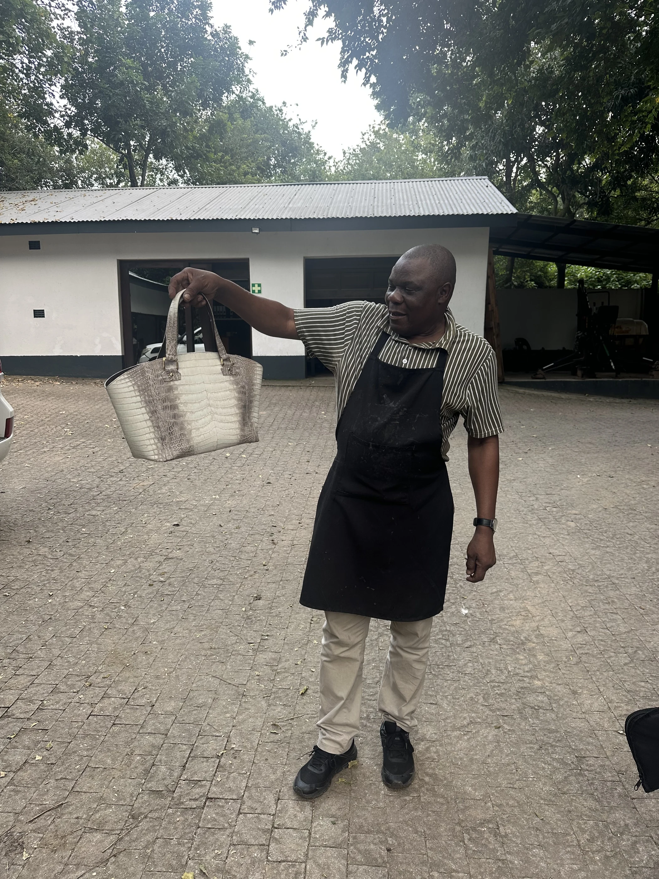 Person holding a finished crocodile leather handbag outdoors