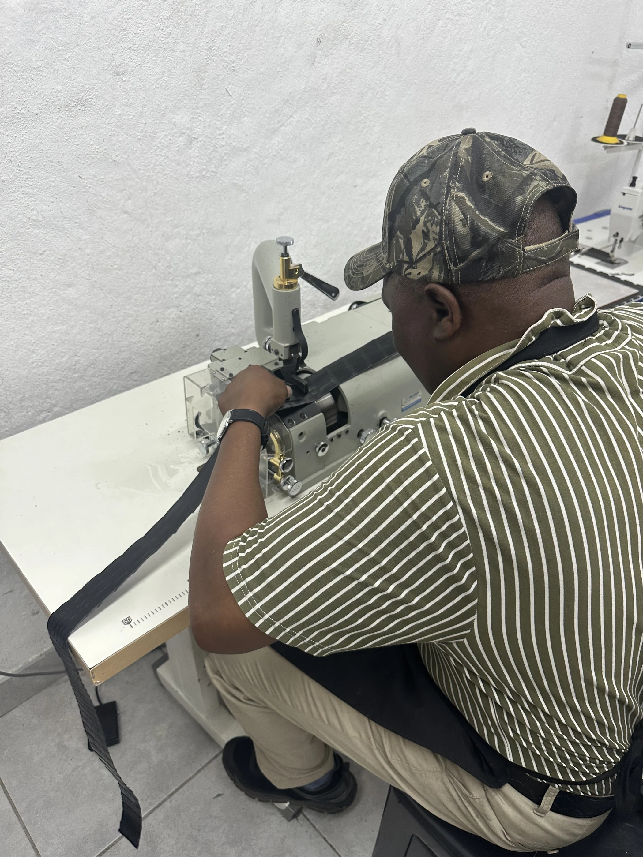 Maker guiding dark material through a sewing machine