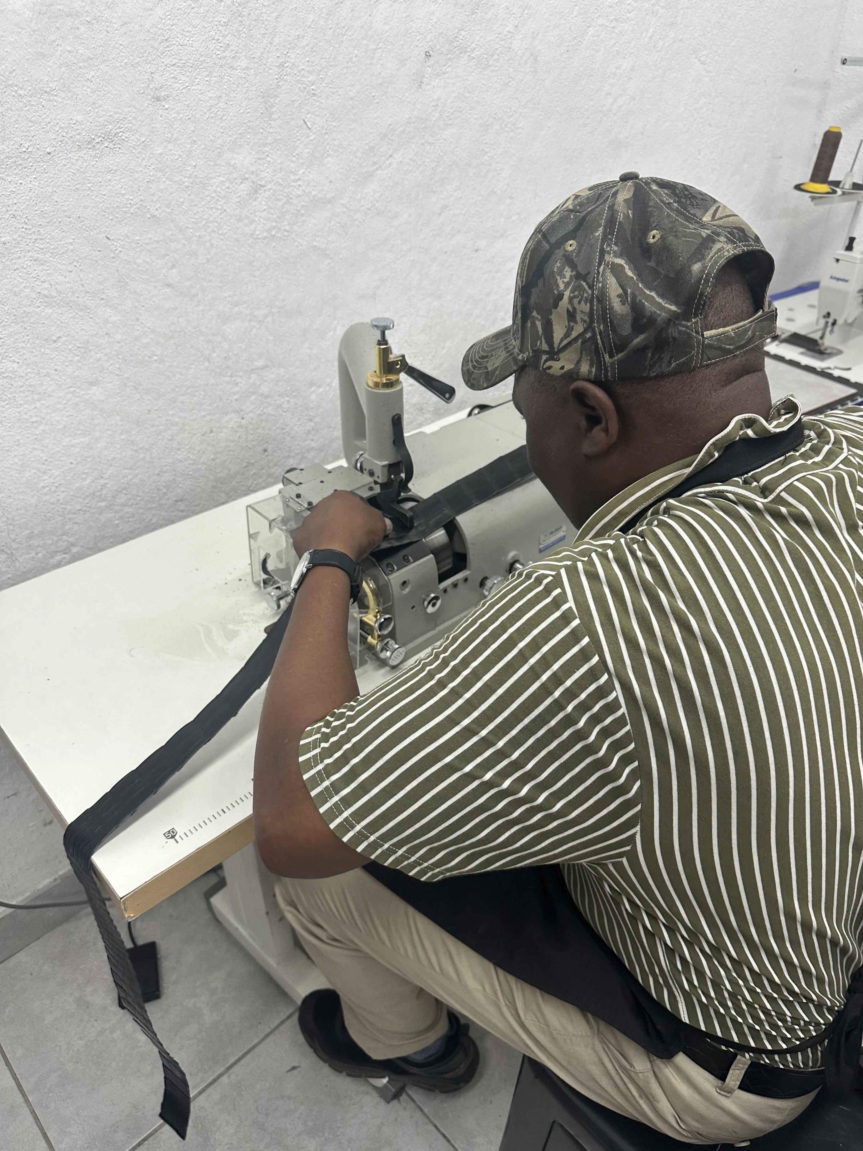 A craftsperson guides a crocodile leather strip through a machine