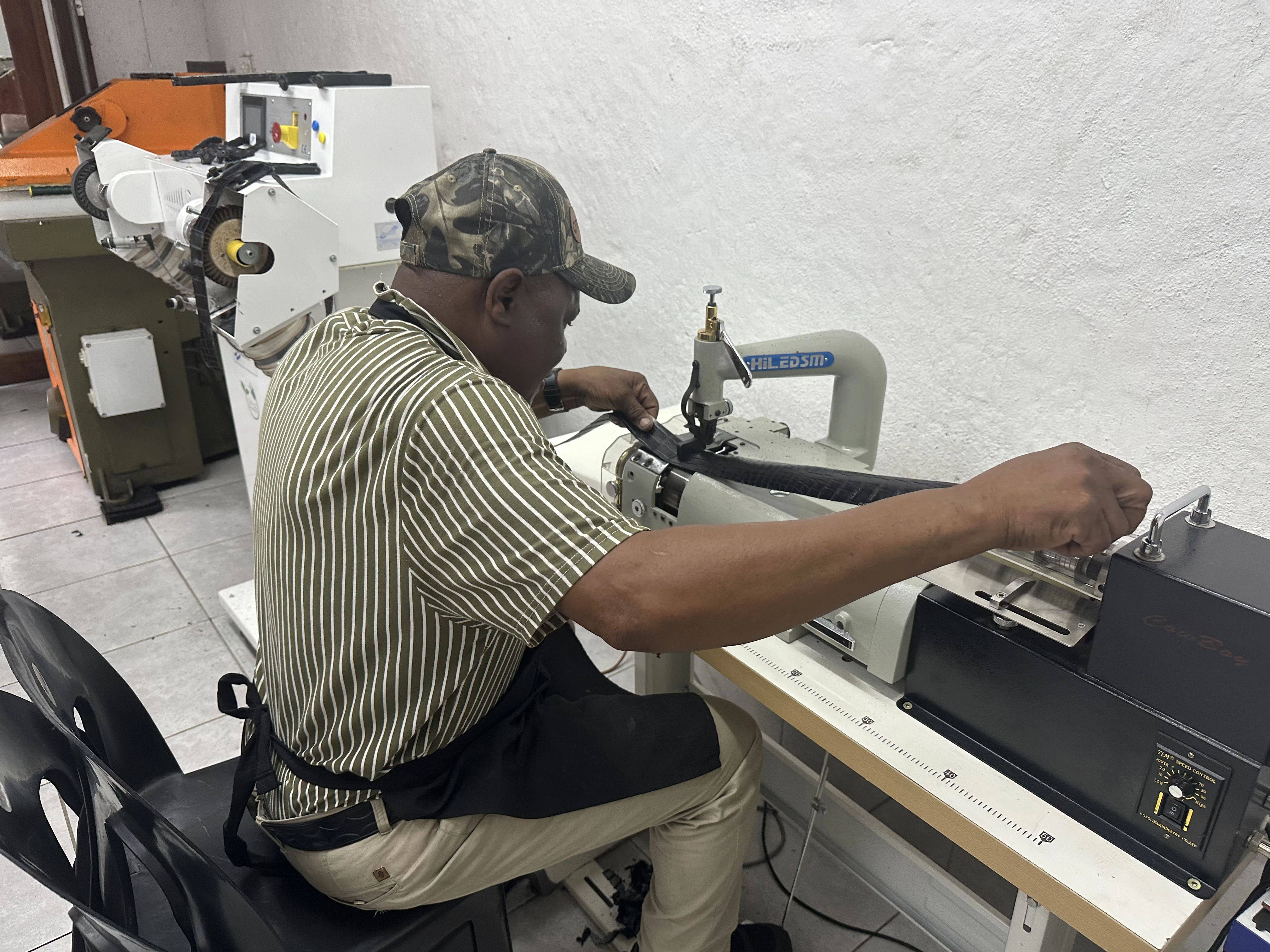 A craftsperson works a strip of crocodile leather at a machine in the Seronera atelier